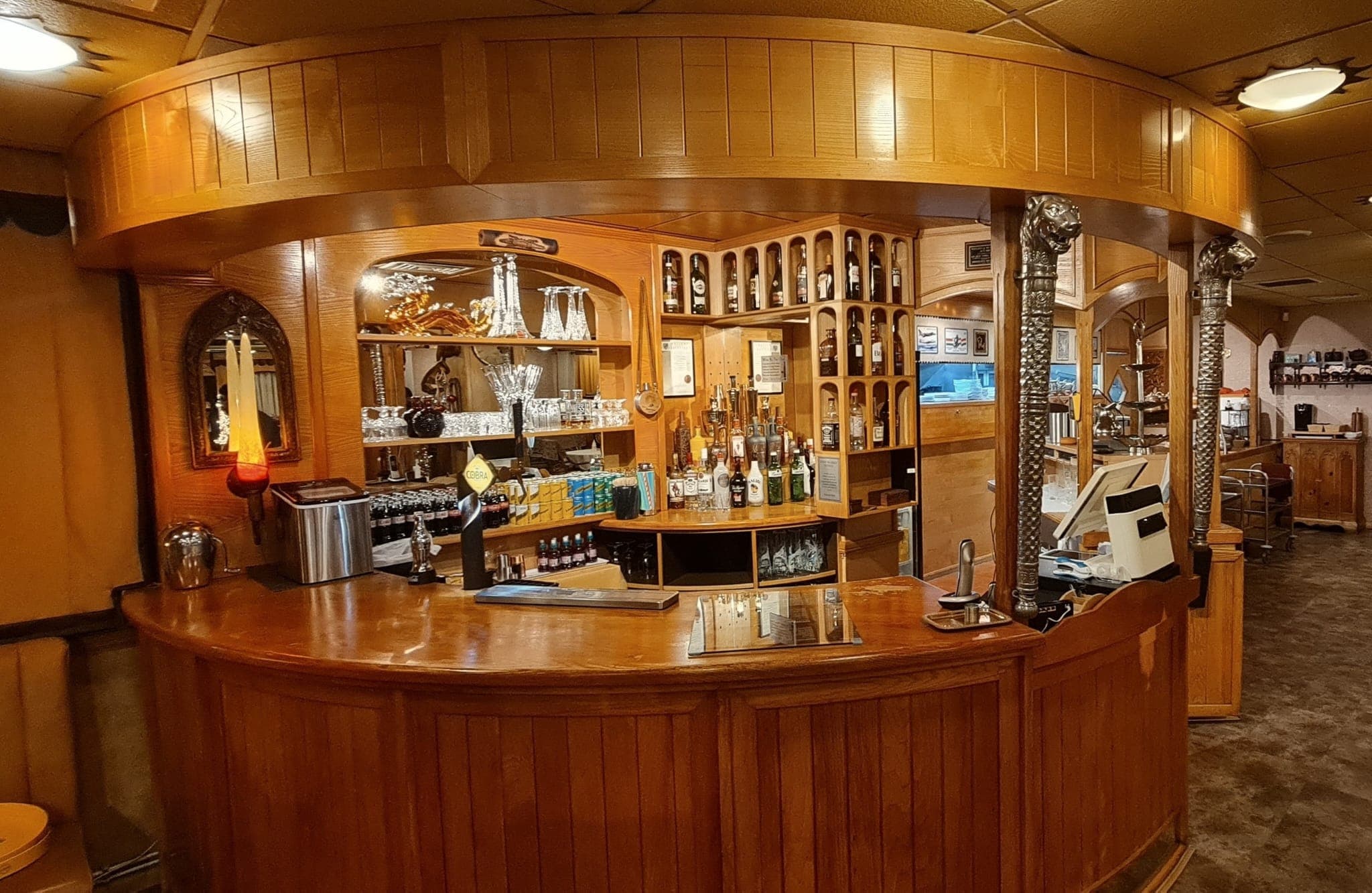 Curved wooden bar with bottles and glassware